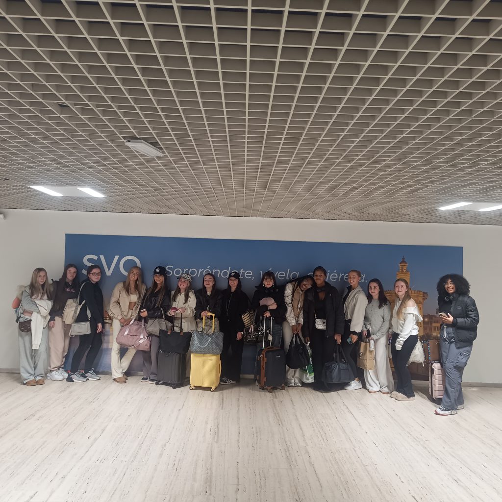 The Travel and Tourism students lined against the wall in the airport posing for a photograph before catching their flight to Seville 